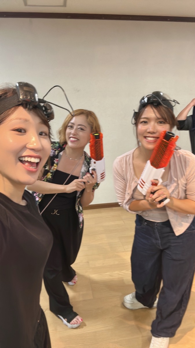 ブラスターを手に笑顔でセルフィーを撮る女性3人組